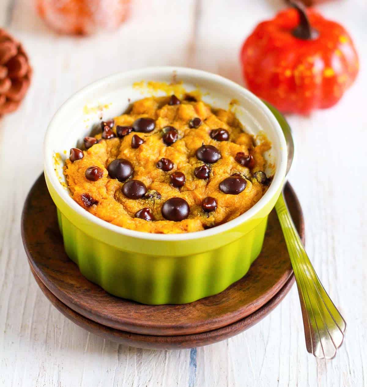mug cake in a green ramekin on a plate with a spoon on the side.