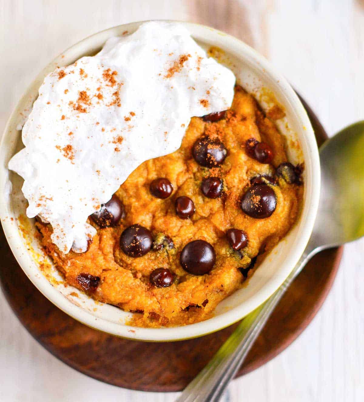 Pumpkin mug cake with chocolate chips and whipped cream.