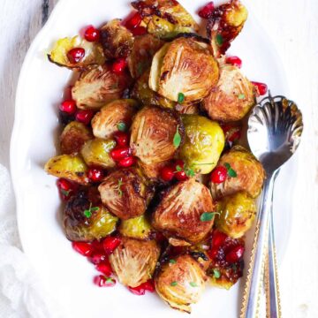 roasted brussels sprouts on a white platter with spoon.
