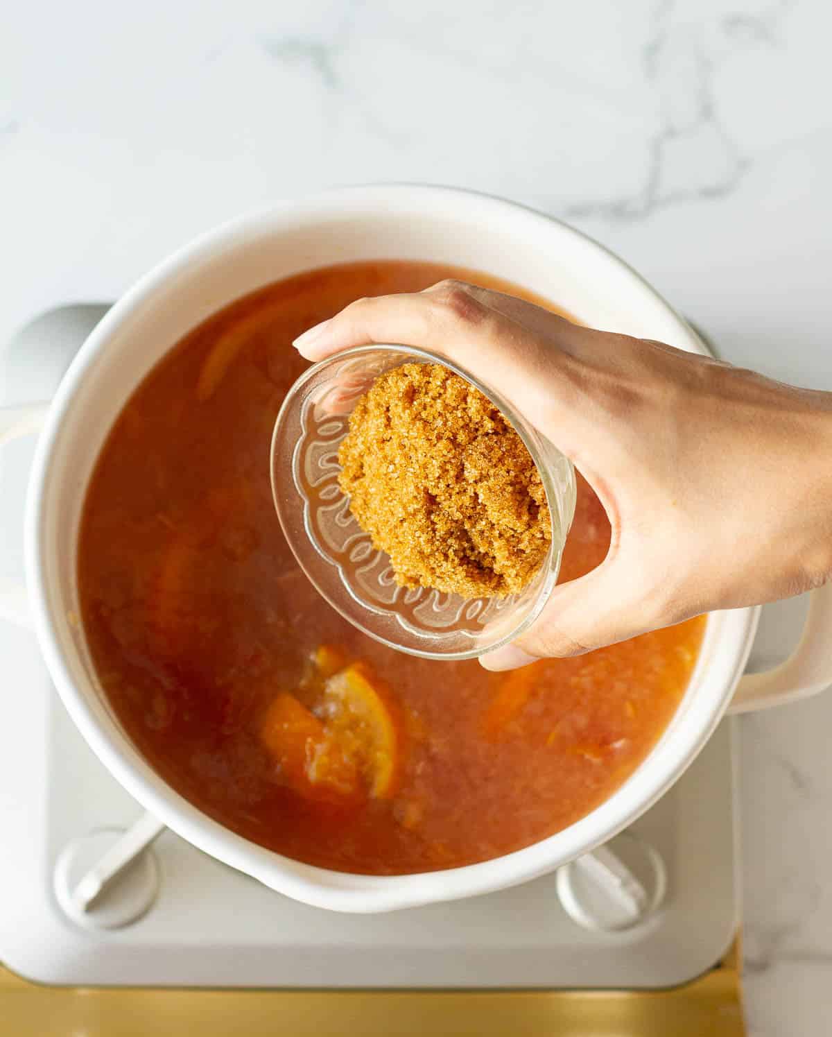 Adding brown sugar to the apple cider.