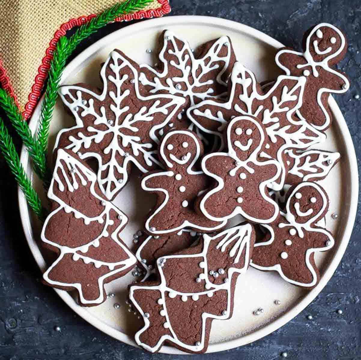 gingerbread cookies on a platter with christmas decorations on the side.