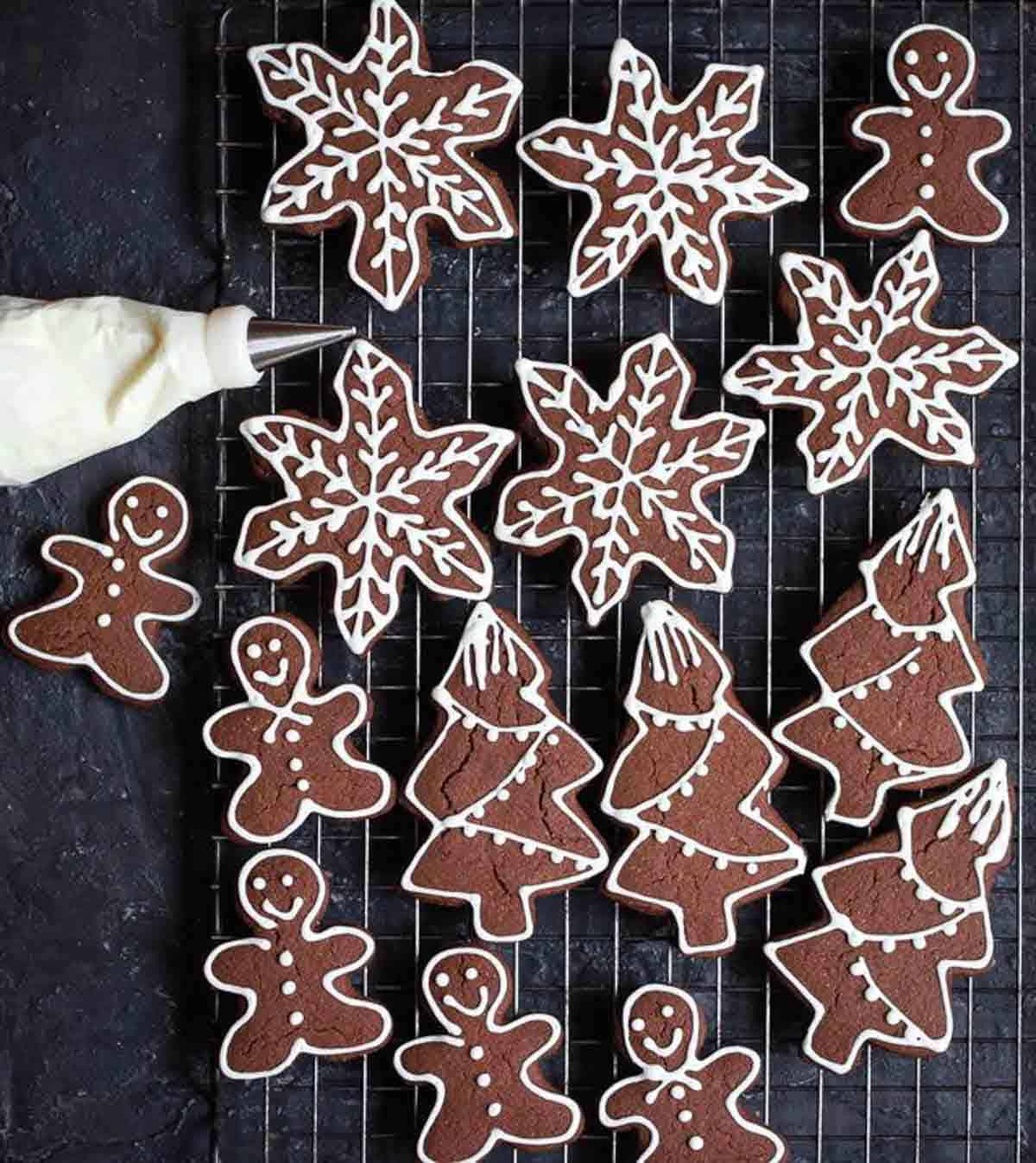 Decorated cookies on a tray with a piping bag with white icing on the side.