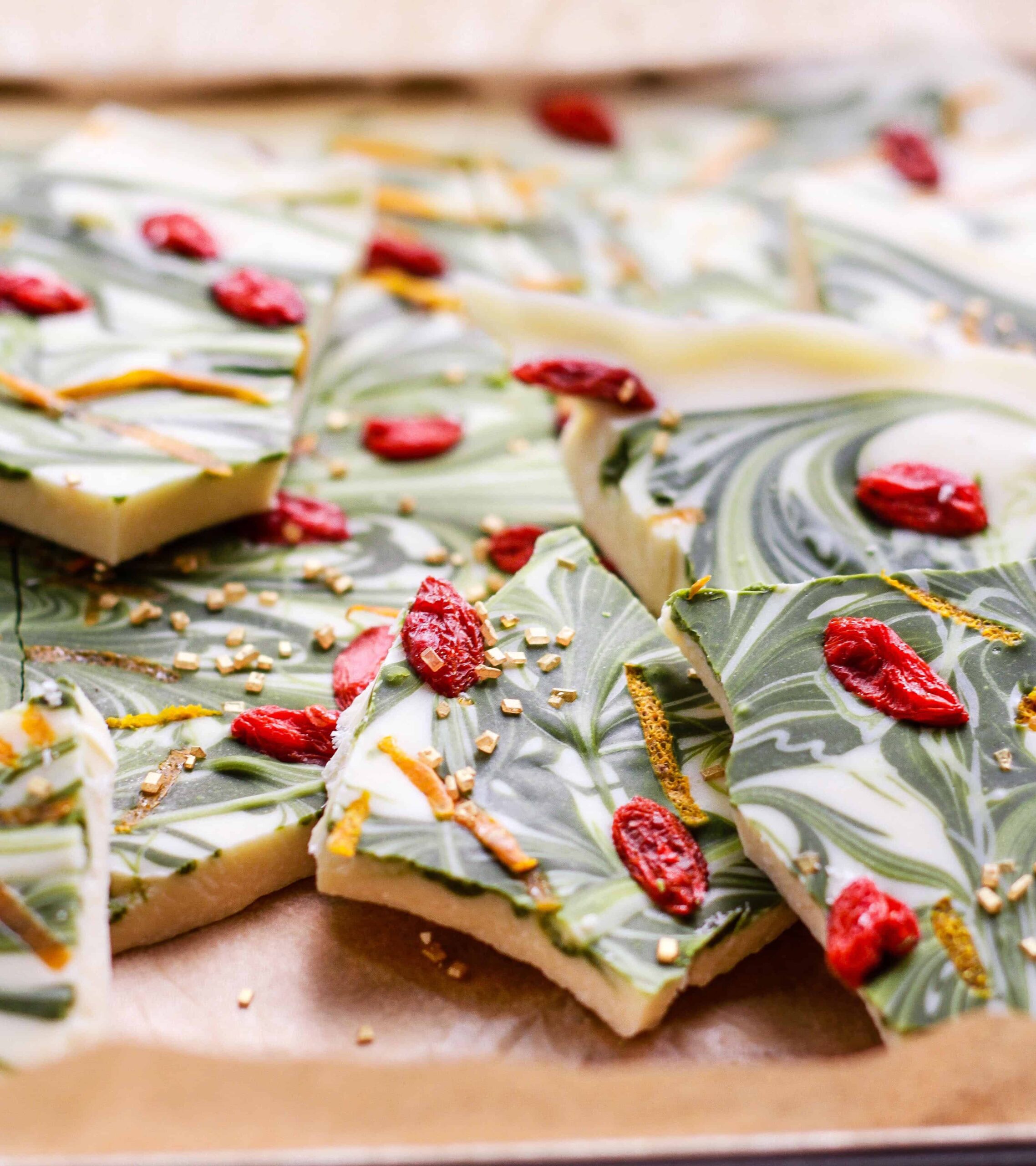 Pieces of white chocolate matcha bark on parchment paper.