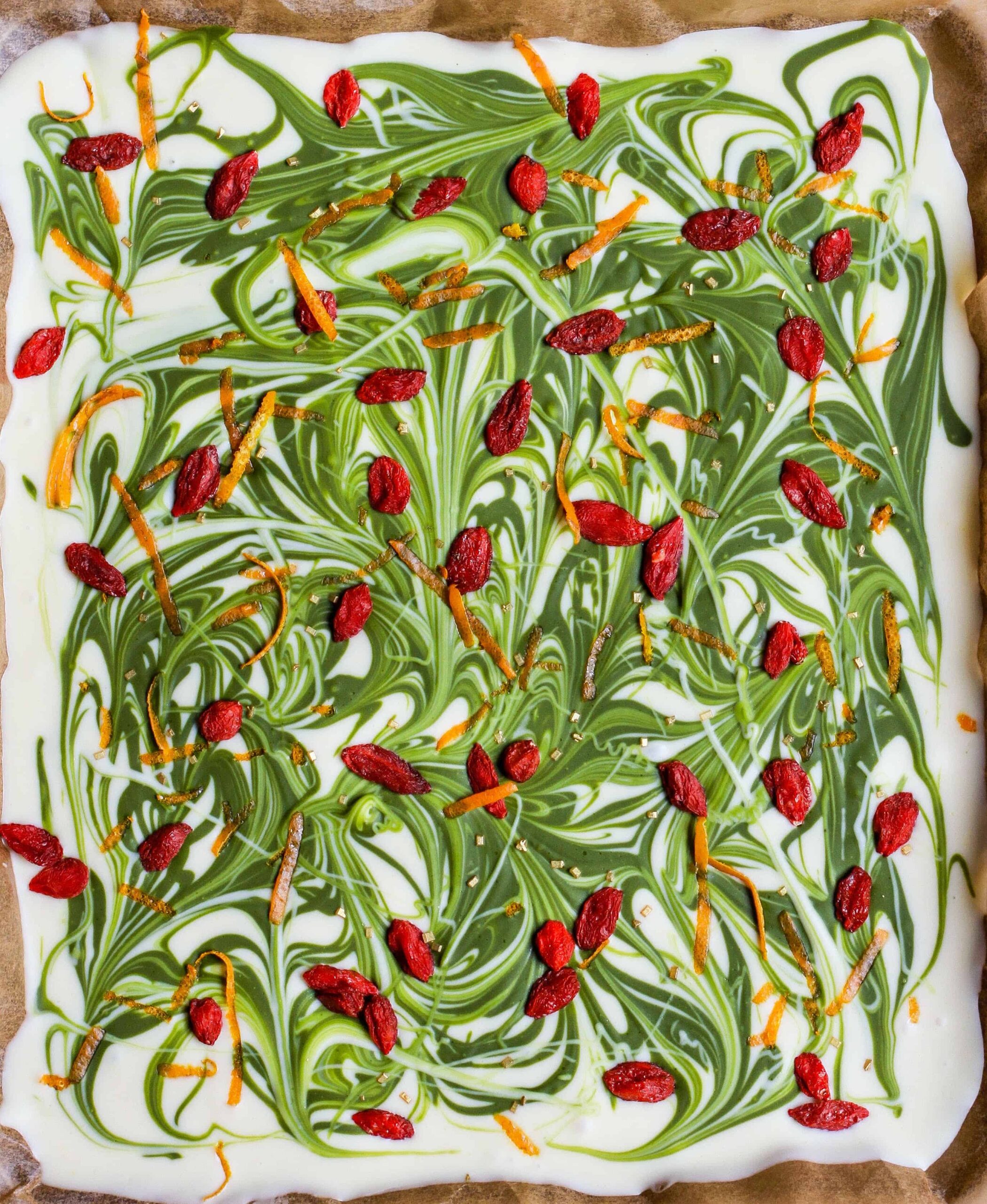 White chocolate bark with matcha swirls and goji berries on a tray.