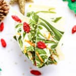 Pieces of white chocolate matcha bark with goji berries stacked.