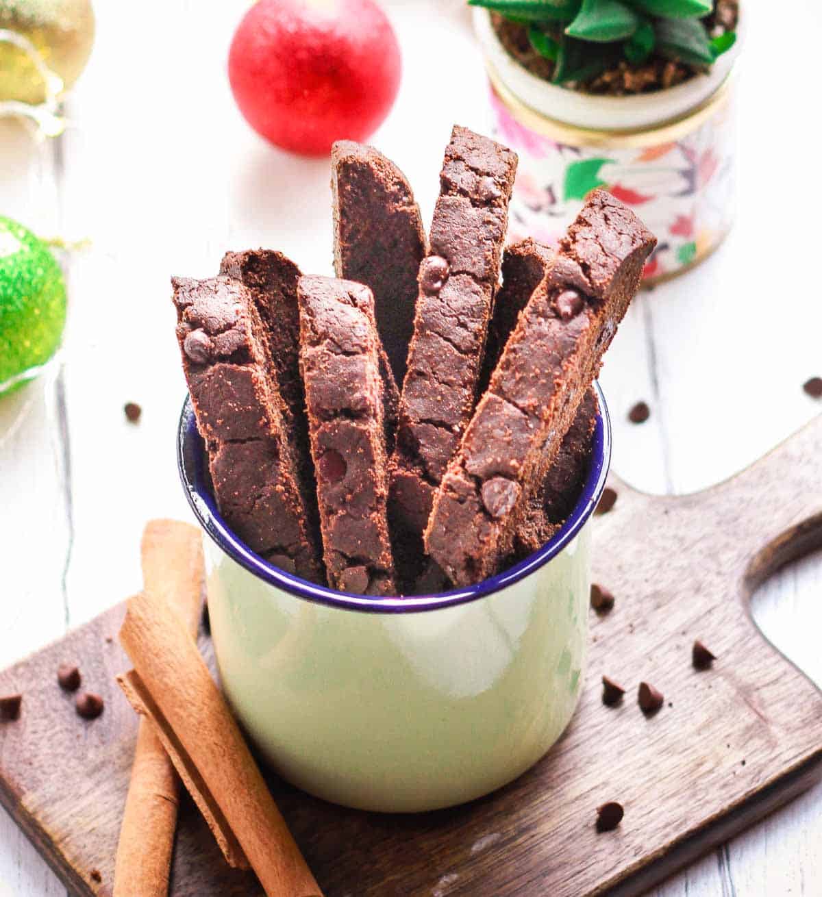 Biscotti in an enamel green mug with ingredients around.