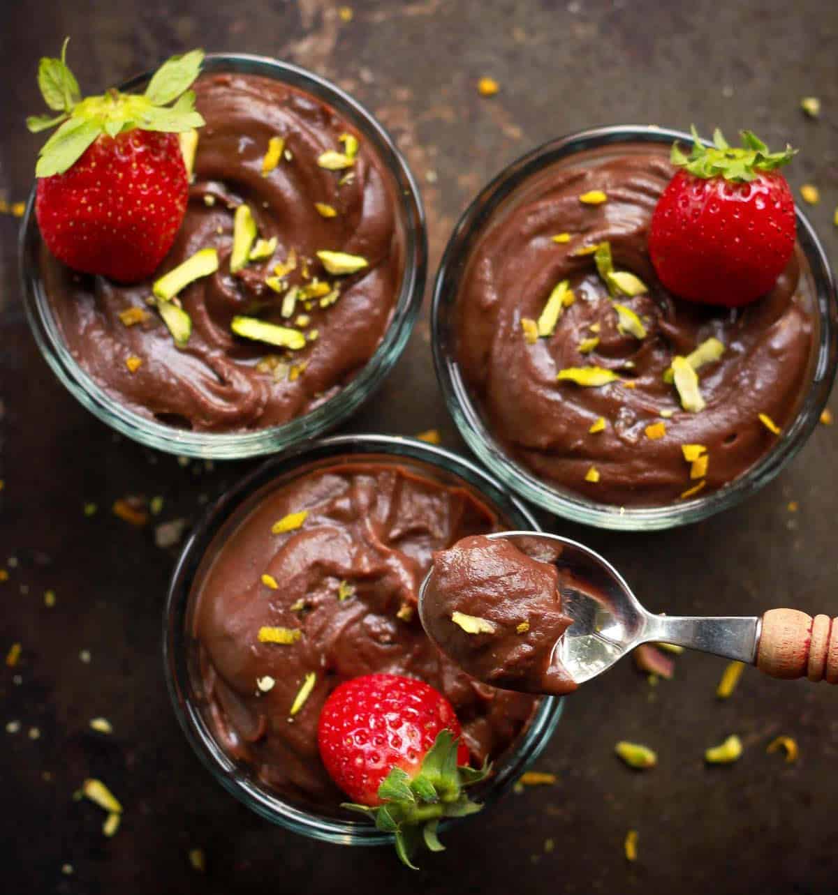 A spoonful of chocolate pudding on top of bowls of pudding.