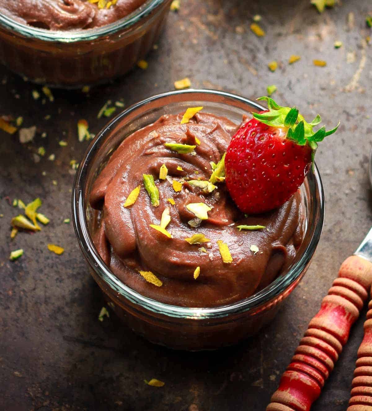 A bowl of sweet potato chocolate pudding with a strawberry and pistachios on top.