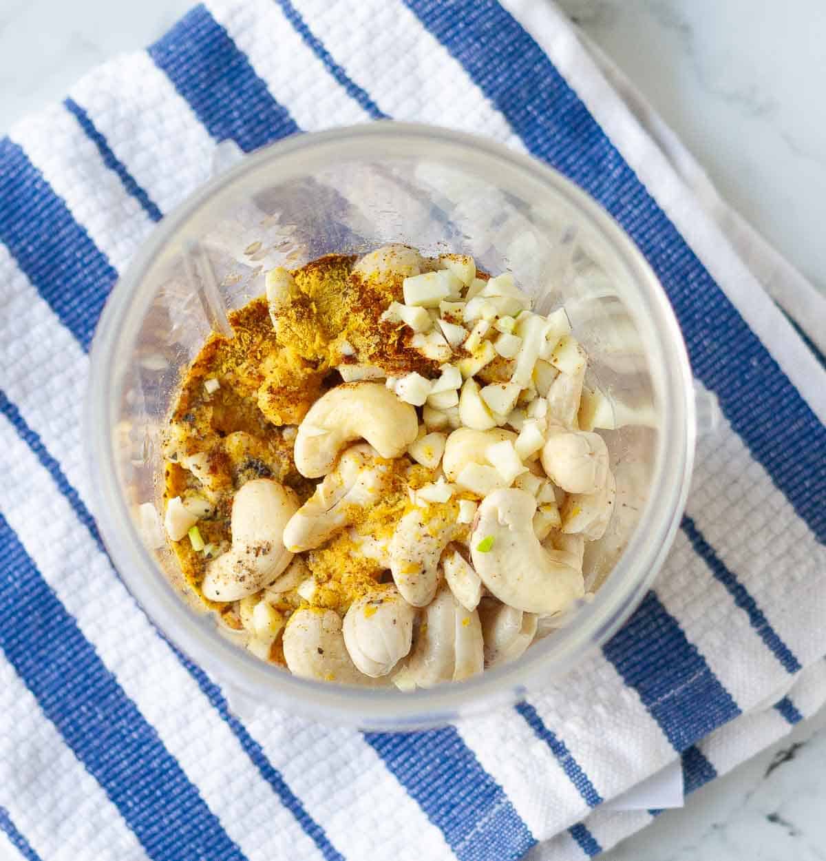 ingredients in a blender jar on a blue striped napkin.