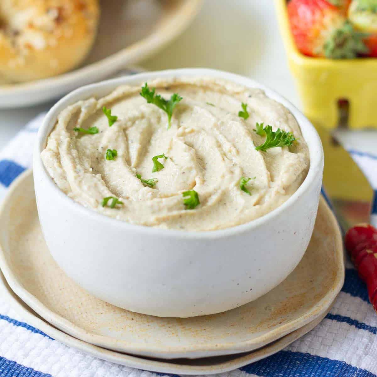 cashew ricotta cheese garnished with parsley in a small bowl place on 2 plates.