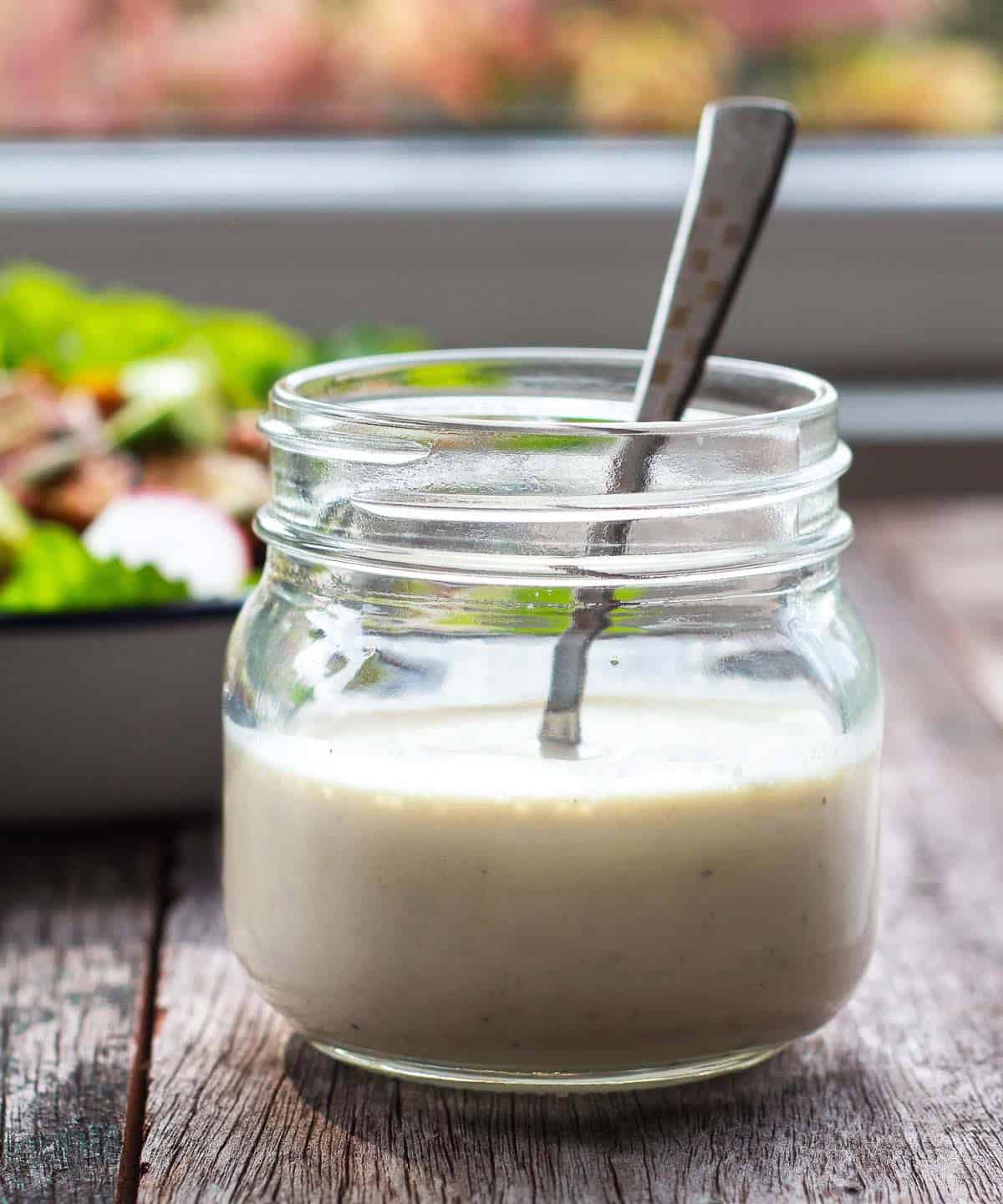 salad dressing in a glass jar with a spoon.