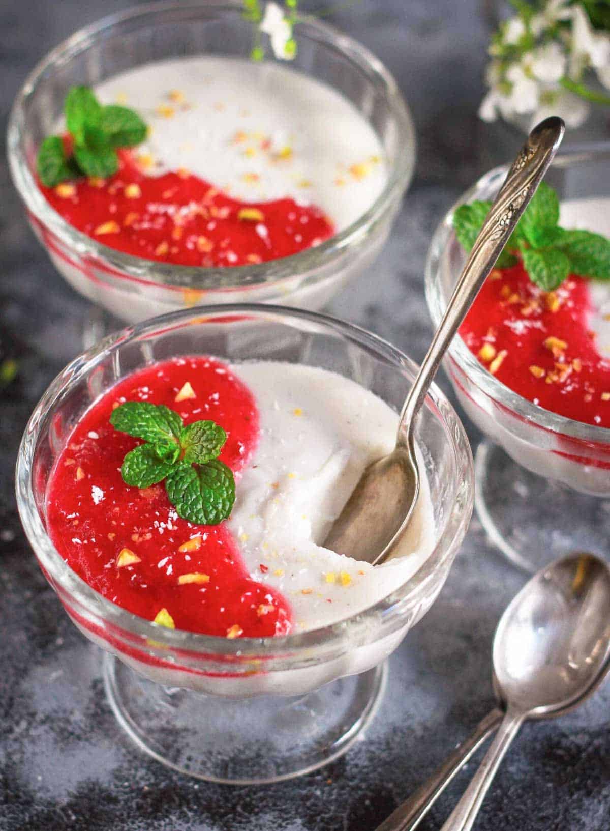 A bowl of panna cotta with a spoon and with a bite taken out.