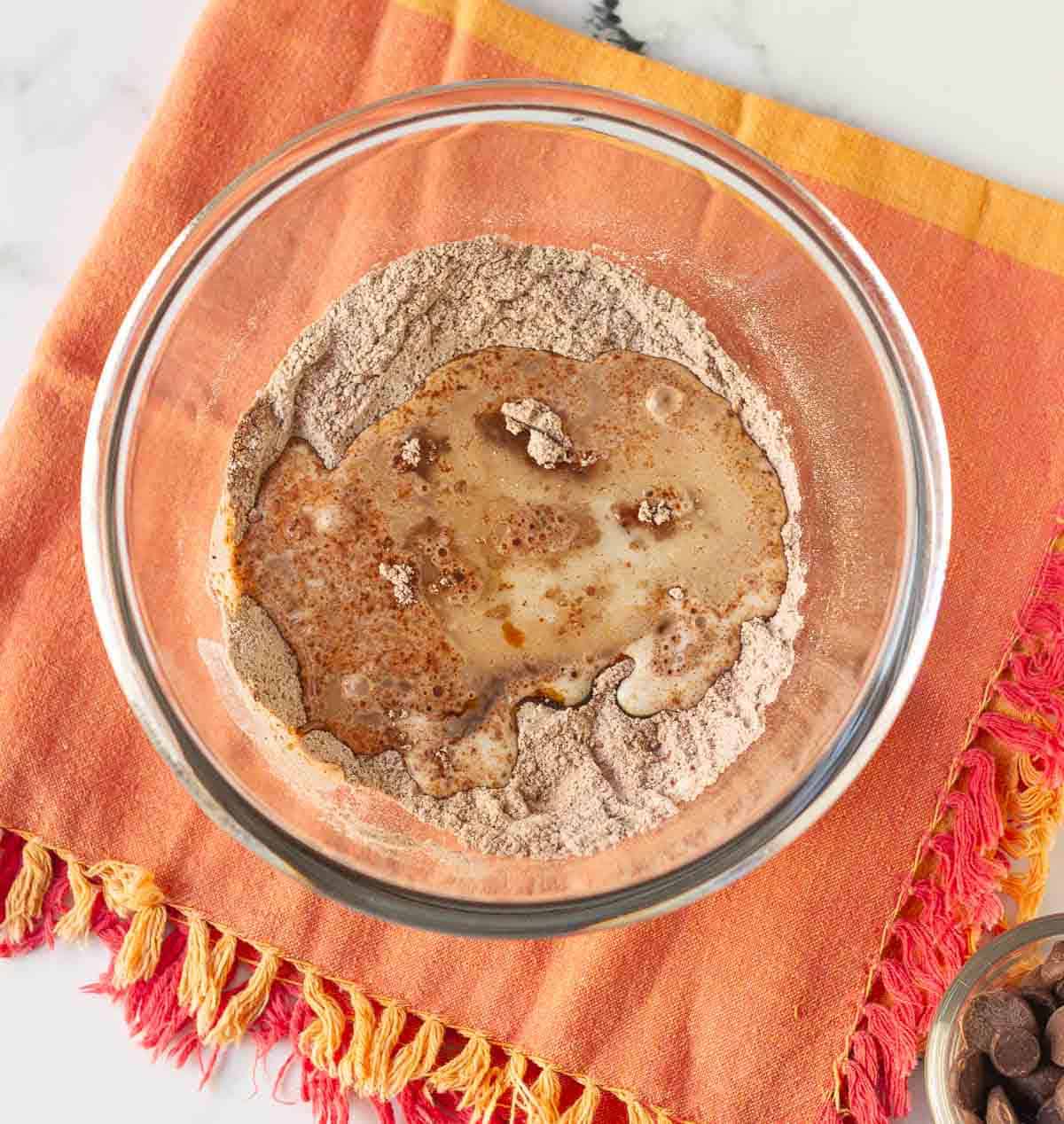 dry and wet ingredients in a glass bowl on a red napkin.