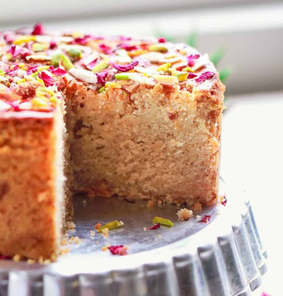 Cake with a slice taken out on a cake stand.
