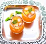 2 glasses of mango margarita with paprika salt on the rims on a tray.