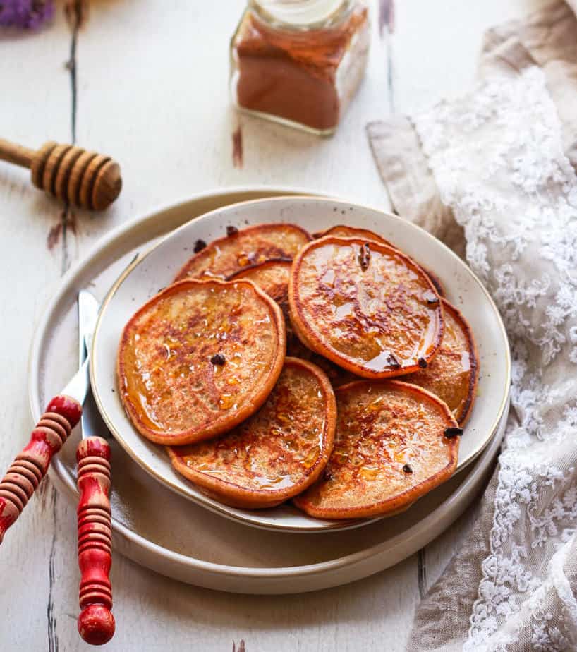 Banana pancakes on a plate with a fork and knife on the side.