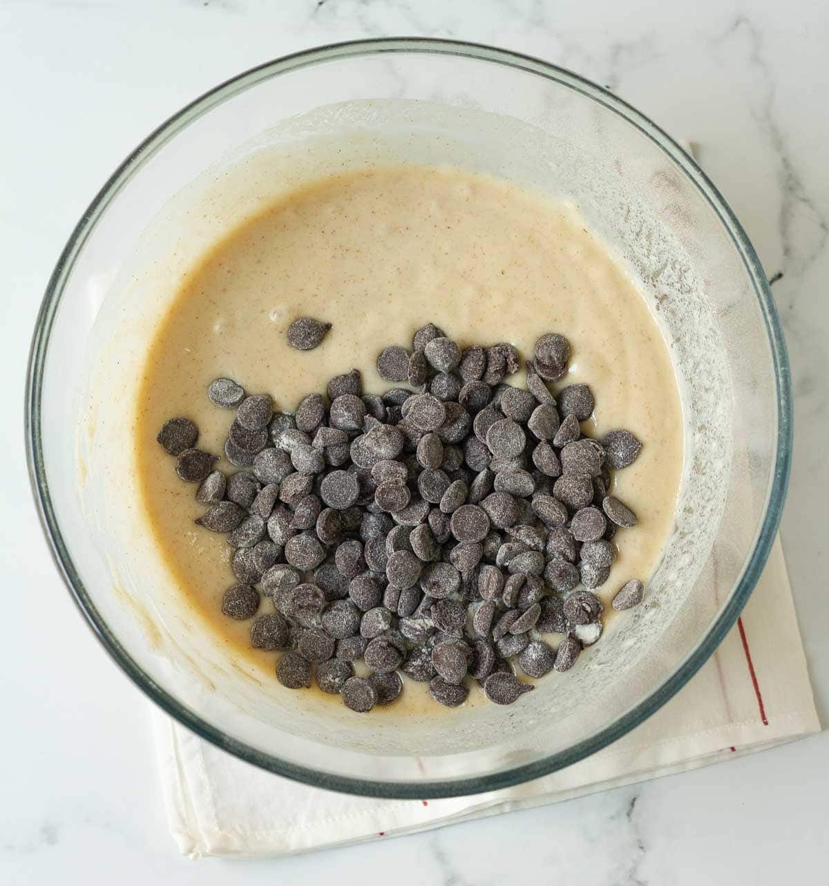 Chocolate chips coated with flour on top of cake batter in a mixing bowl.