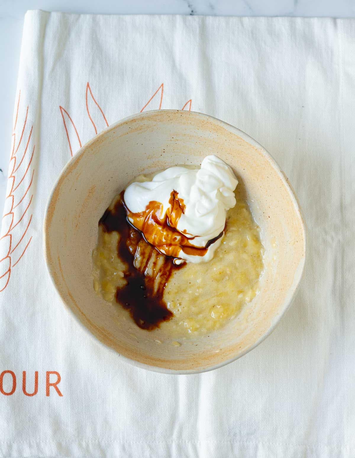 Mashed banana, cream, and vanilla extract in a bowl.