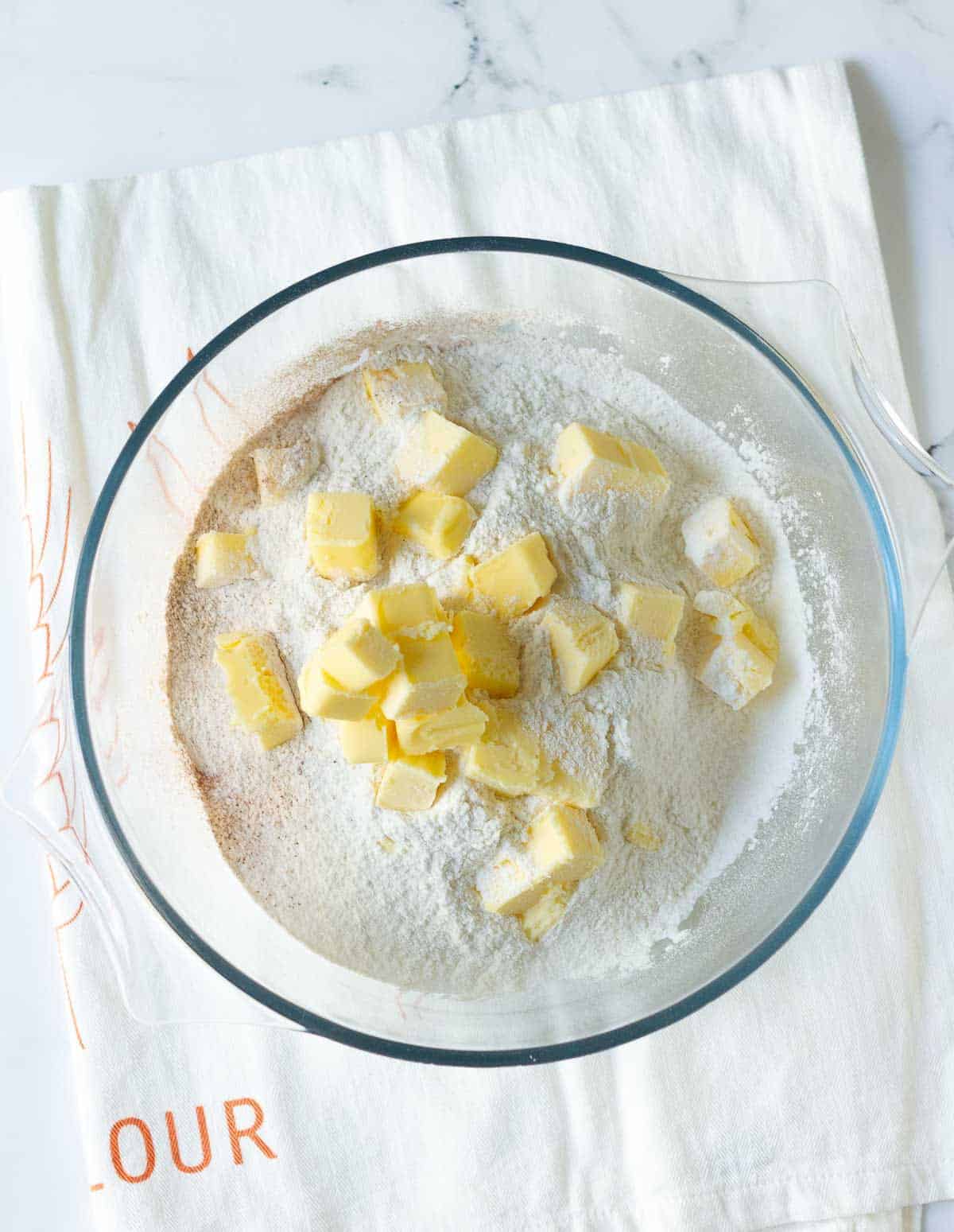 Cubed butter on top of dry ingredients in a mixing bowl.