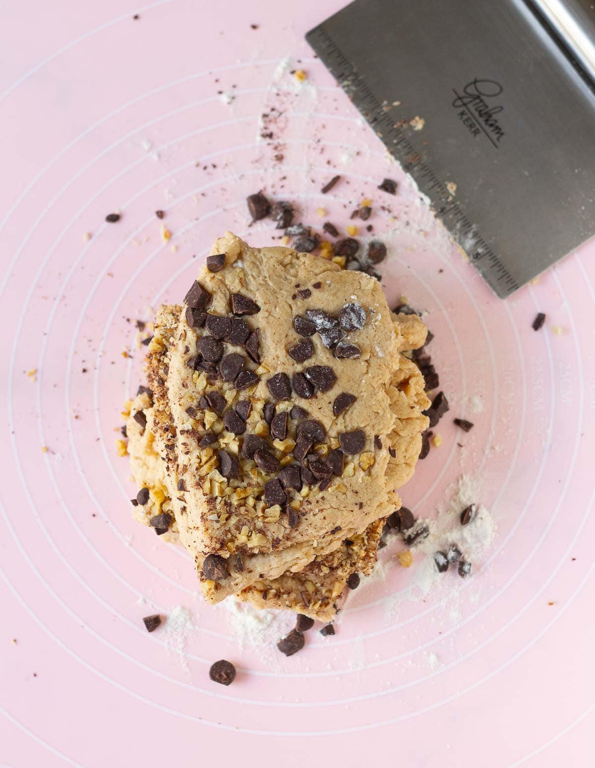 Dough mixed with chocolate chips and walnuts on a silicone mat.