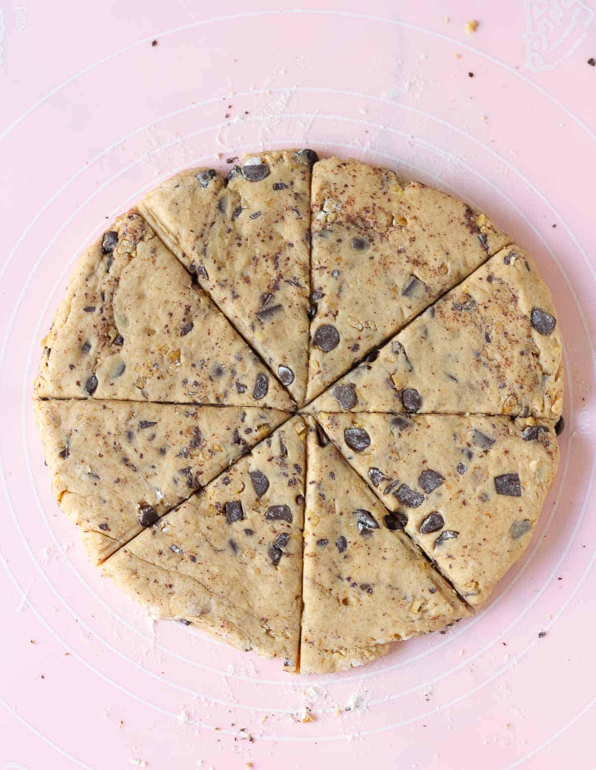 Rolled out dough cut into 8 triangles on a pink baking mat.