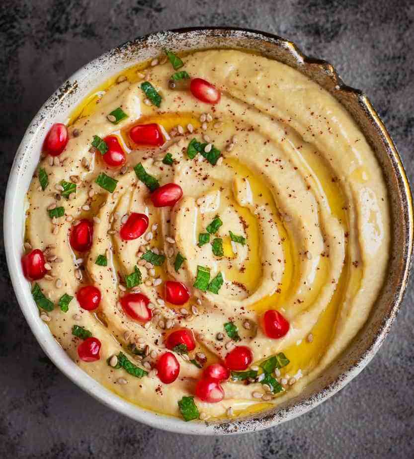 Hummus in a bowl topped with pomegranates.