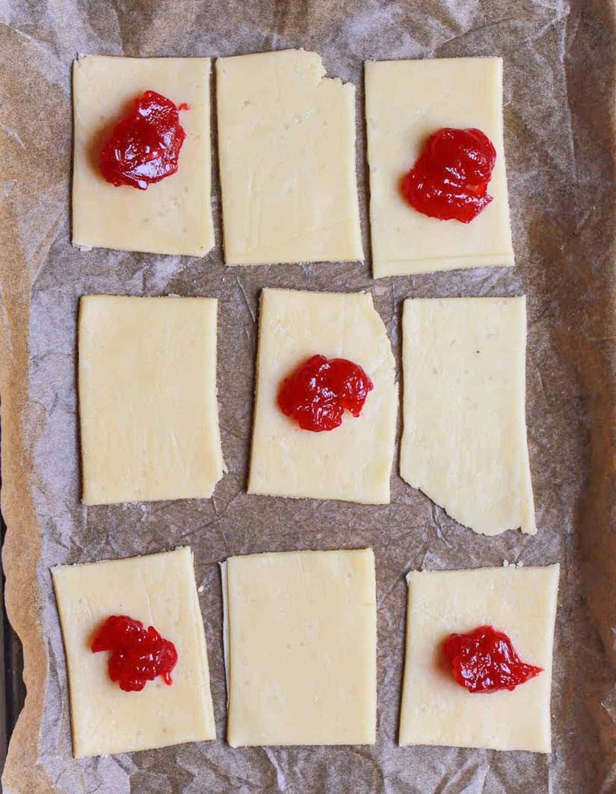 spoonful of strawberry jam in the center of five pastry rectangles.