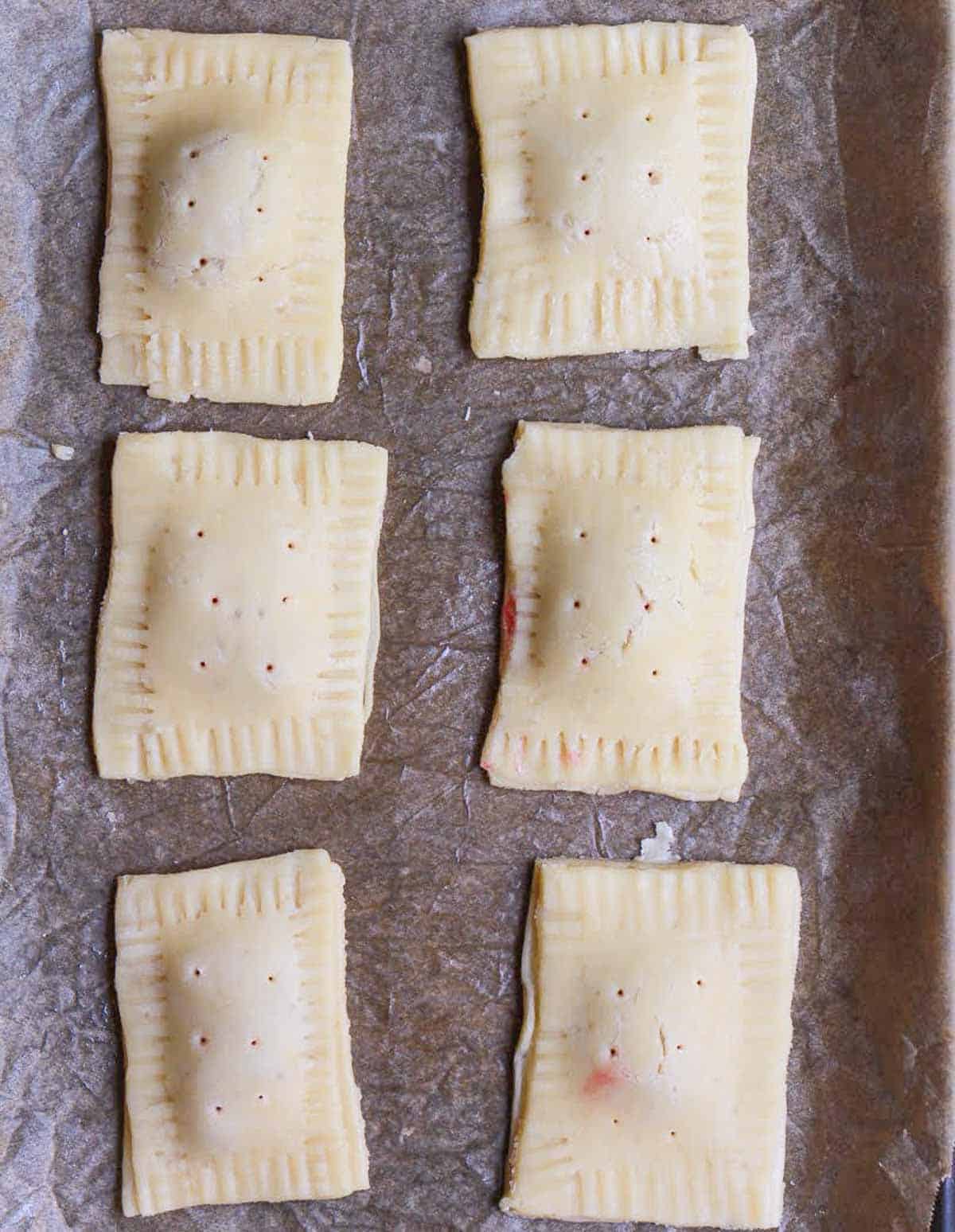 six pastry rectangles with crimped edges and holes on the top.