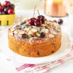 Fresh cherry cake with cherries on top on a platter.