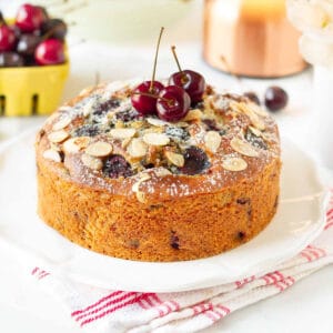 Fresh cherry cake with cherries on top on a platter.