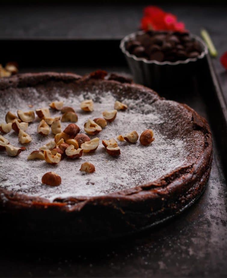 Chocolate cake topped with powdered sugar and hazelnuts.