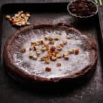 Swedish chocolate cake topped with powdered sugar and hazelnuts on a tray.