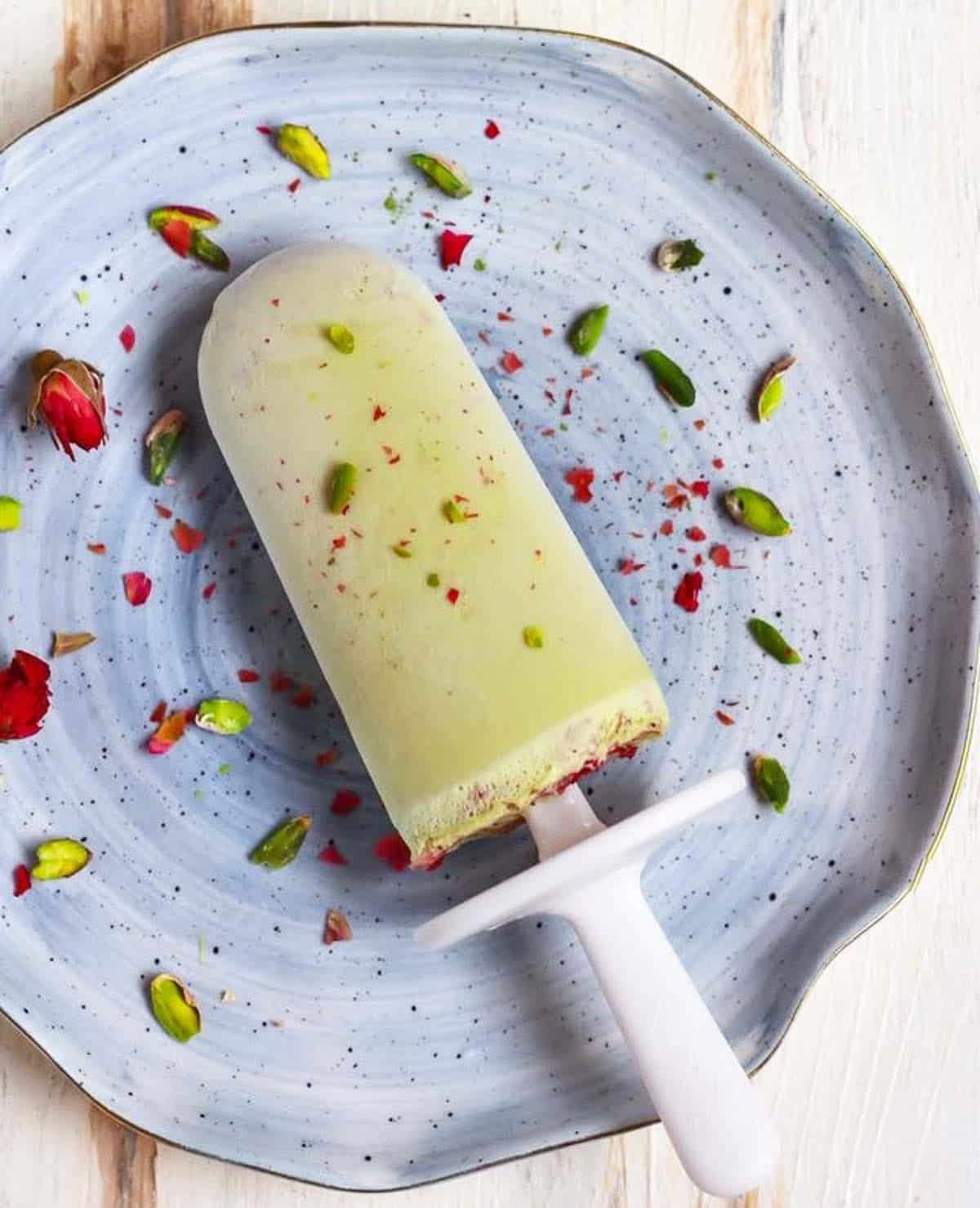 Pistachio matcha popsicle on a blue plate.