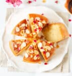 Sliced cake with almonds on a white platter.