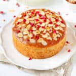Almond honey cake with rose petals and almonds on top on a platter.
