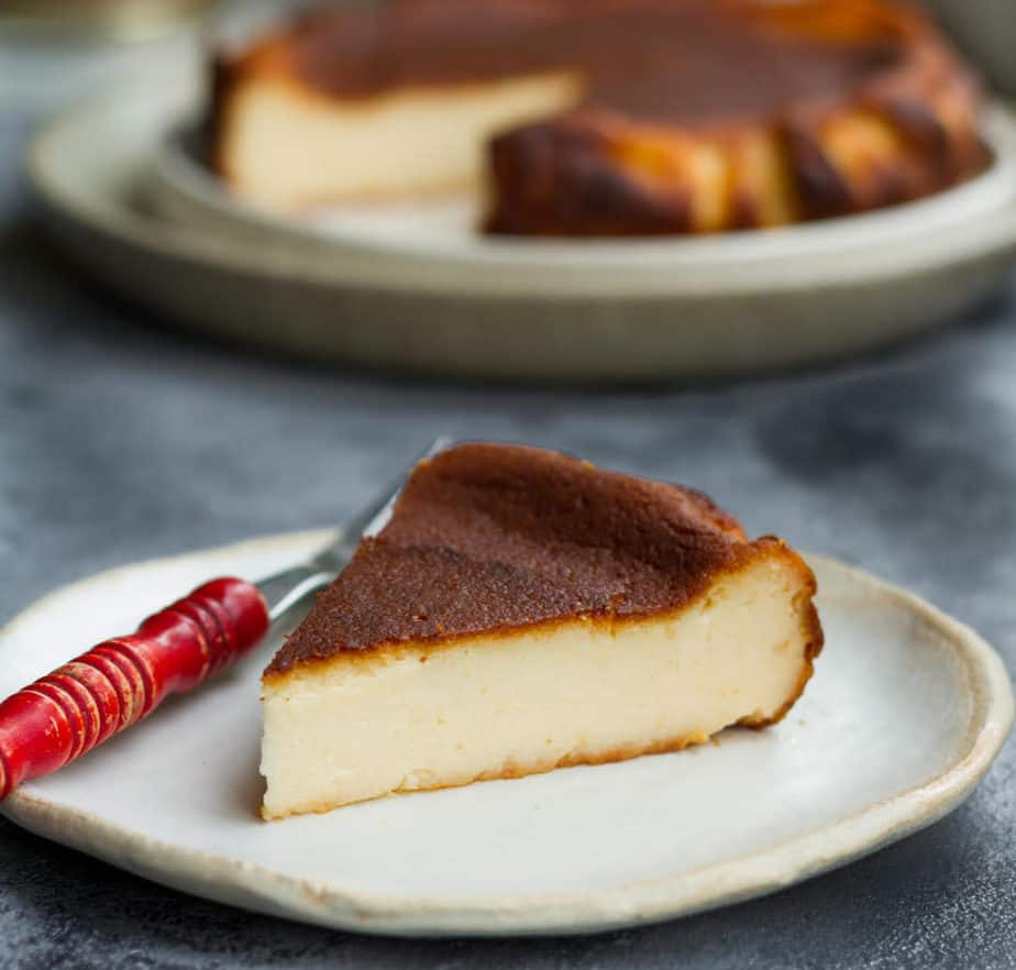 A slice of cheesecake on a palte with a red fork.