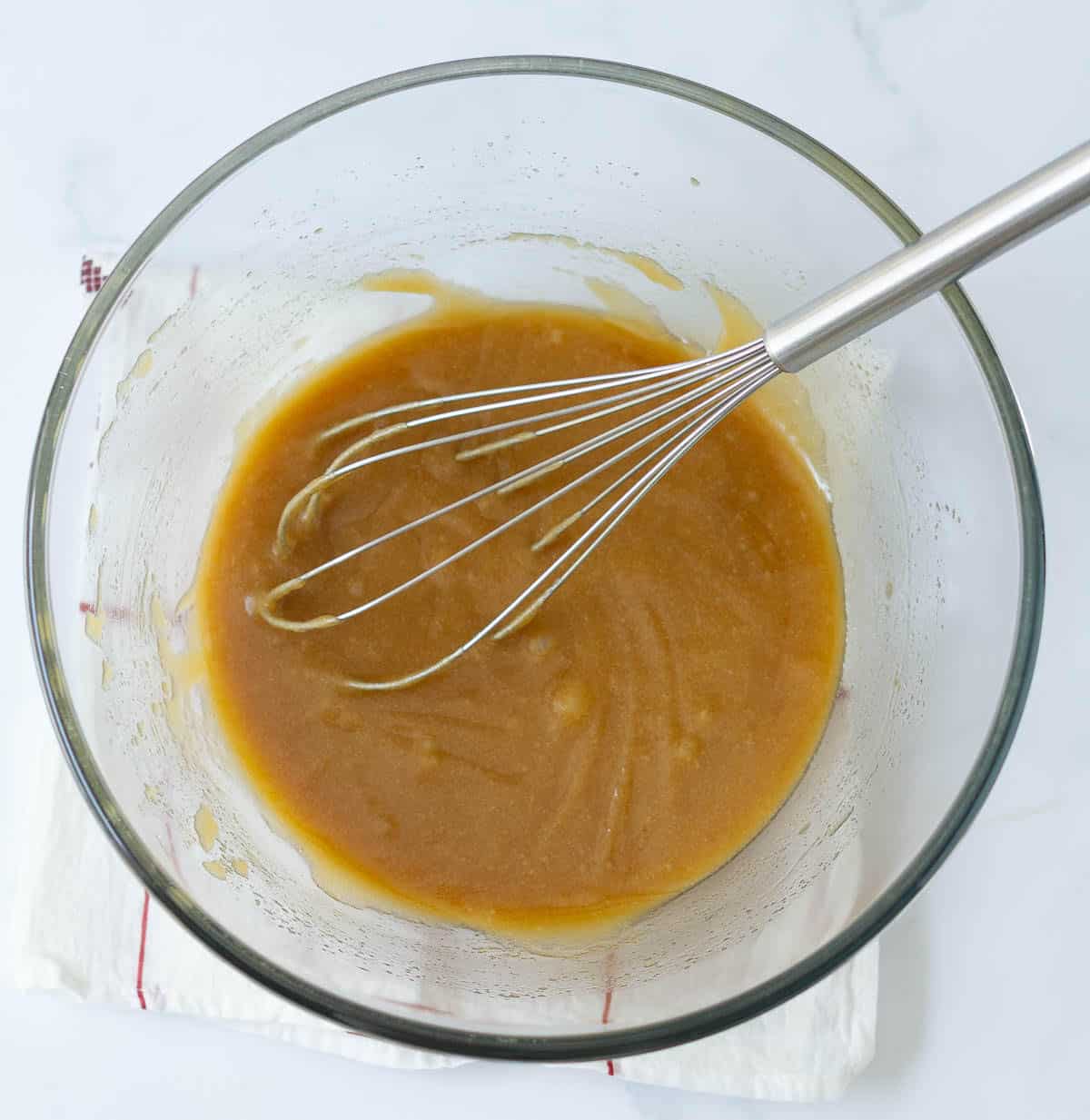 Melted butter and sugar mixture in a mixing bowl with a whisk.