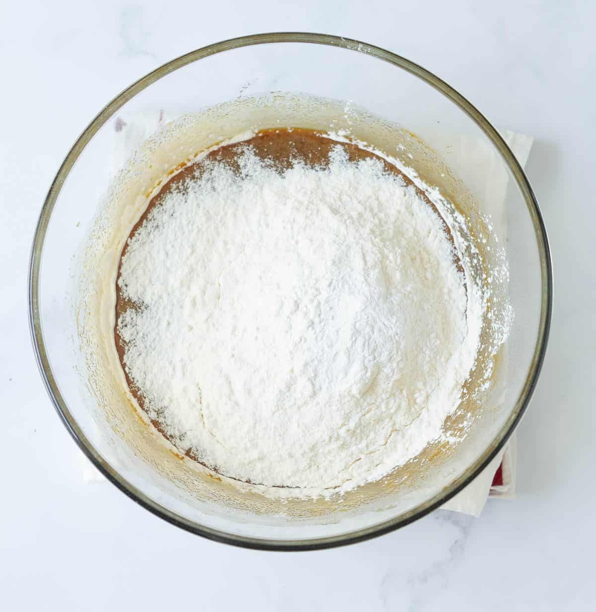 Flour and baking powder on top of butter and eggs mixture.