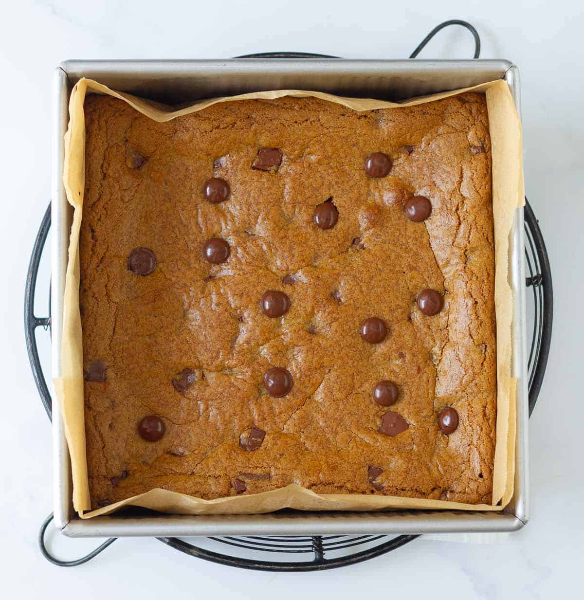 Baked coffee chocolate chip blondies in a parchment paper lined tin.