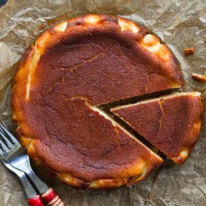basque cheesecake on parchment paper with a slice cut.