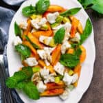 Peach salad with mozzarella on a white platter.