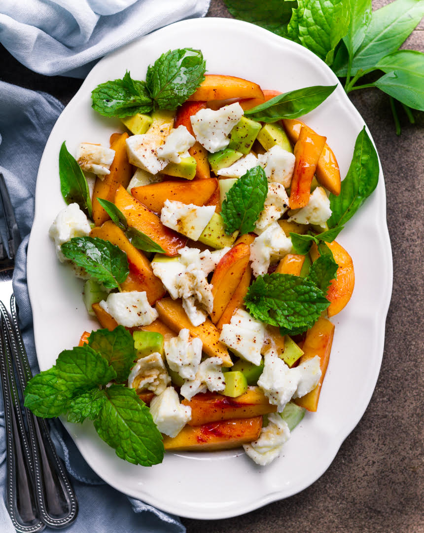 peach and mozzarella salad with mint on a white platter.