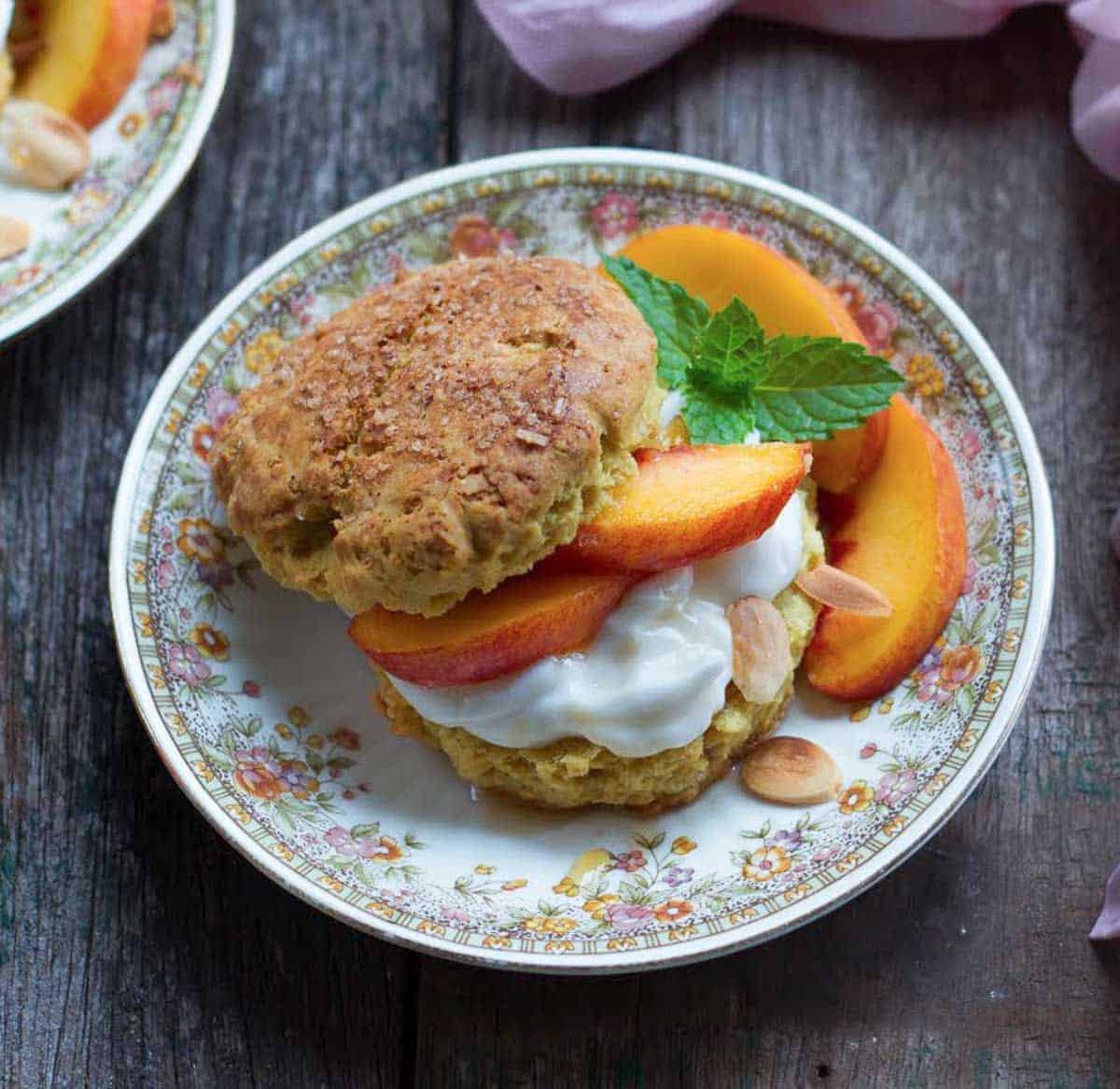 A shortcake with peaches and cream on a small plate.