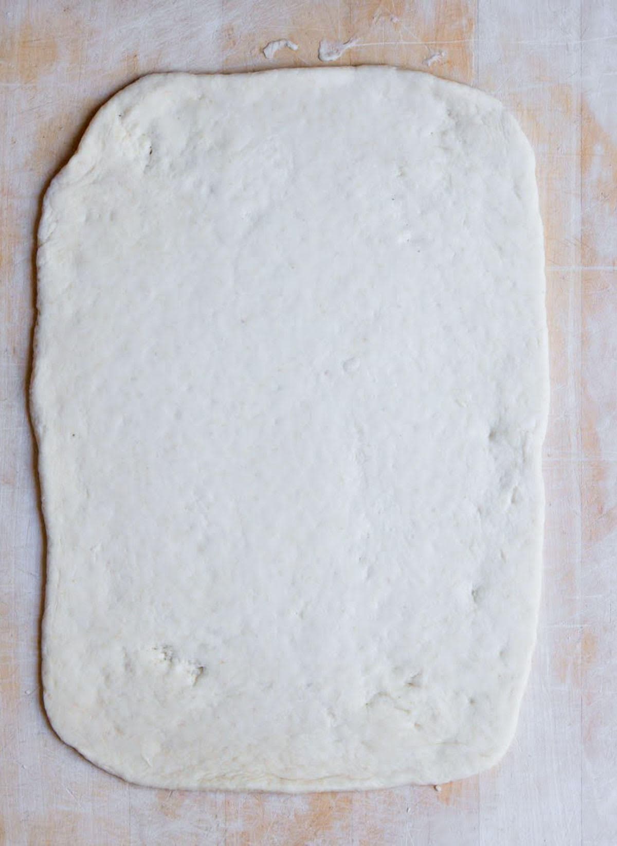 Rolled out dough on a wooden board.