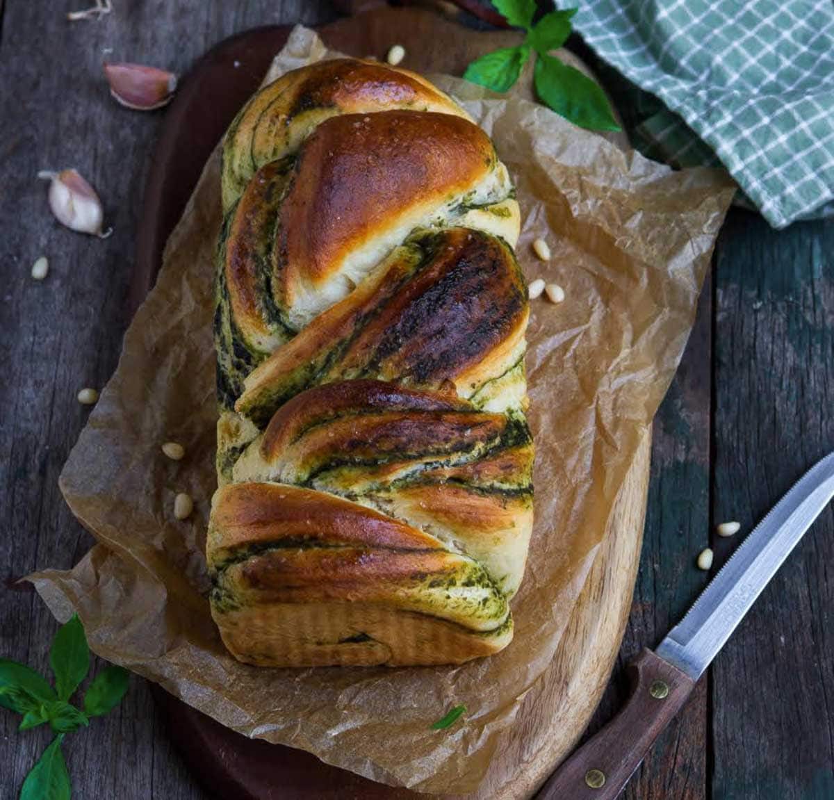 pesto bread on parchment paper with a knife on the side.
