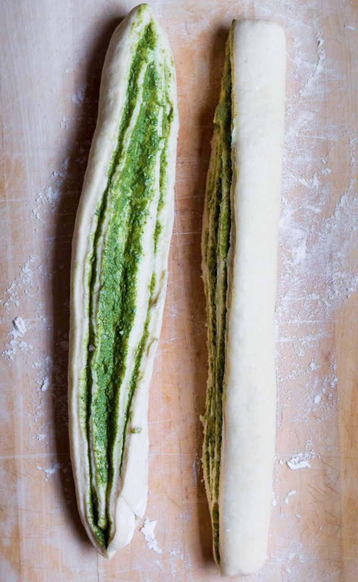 Rolled up pesto bread dough cut into half lengthwise.