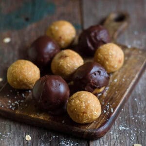 Plain and chocolate coated protein balls on a wooden board.