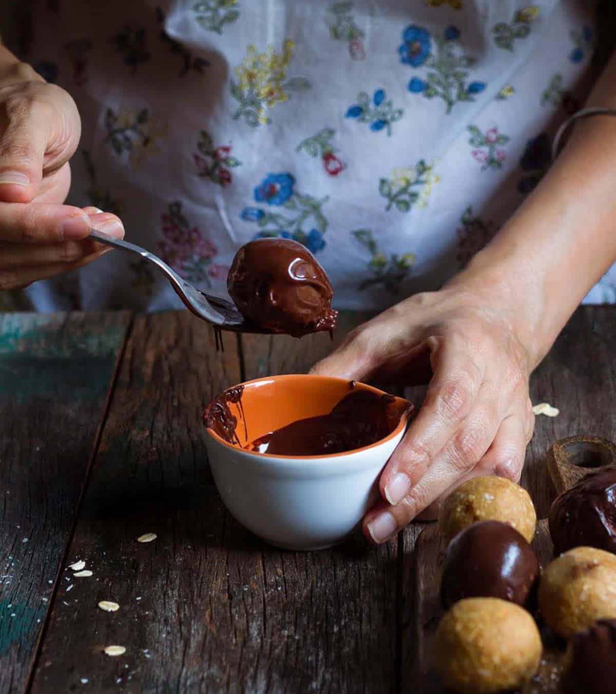 A hand holding a fork with a chocolate covered ball.