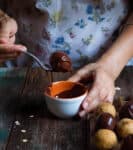 A hand holding a fork with a chocolate covered ball.
