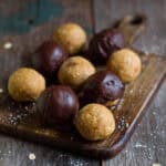 Plain and chocolate coated protein balls on a wooden board.